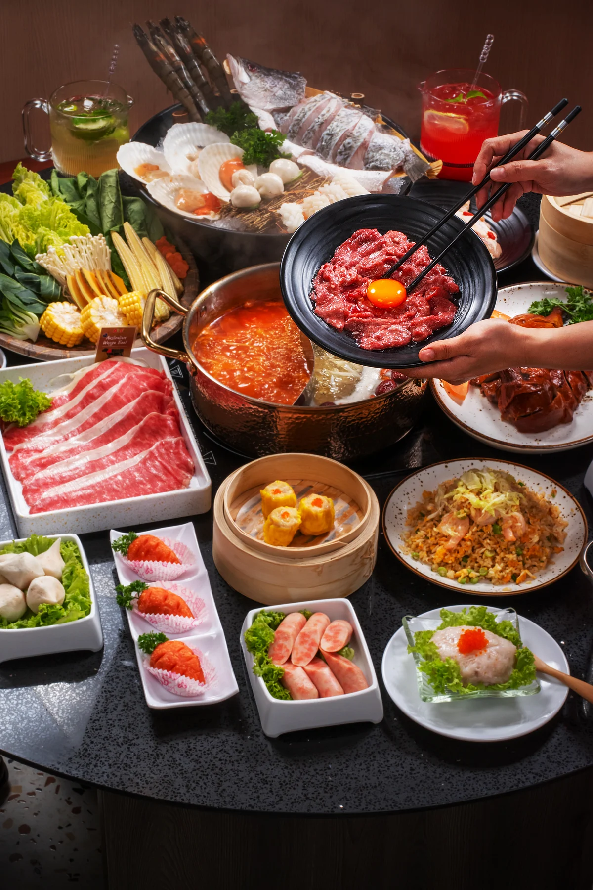 Hot pot feast with raw beef, seafood, vegetables, dumplings, and a bowl topped with egg yolk