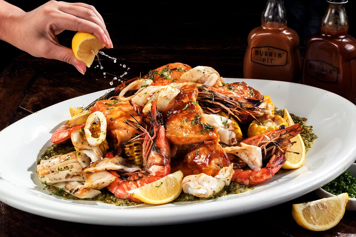 Burnin' Pit grilled seafood platter with prawns, squid, glazed fish, corn, chimichurri and lemon.