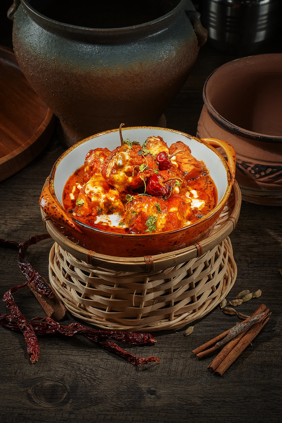 Red curry served in a ceramic bowl with cream, dried chilies and whole spices