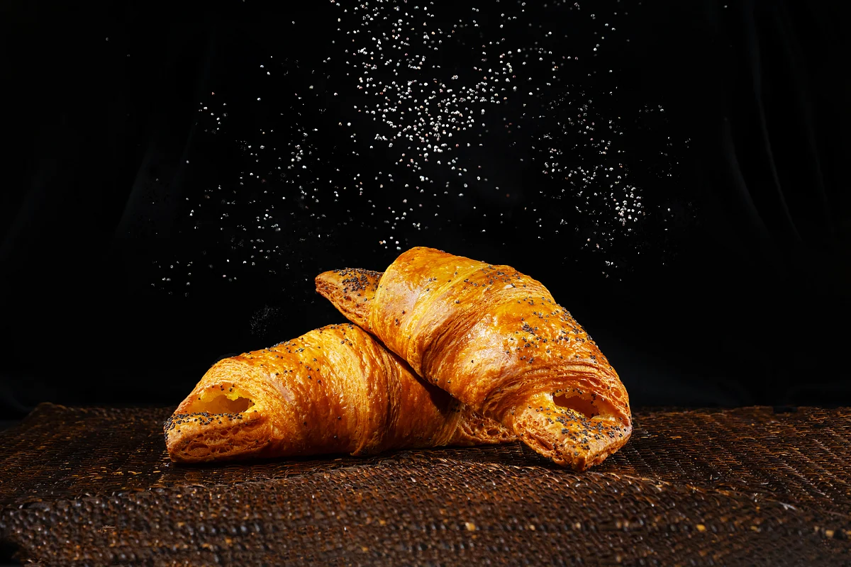 Golden croissants on a cooling rack with pastry tools on a wooden table