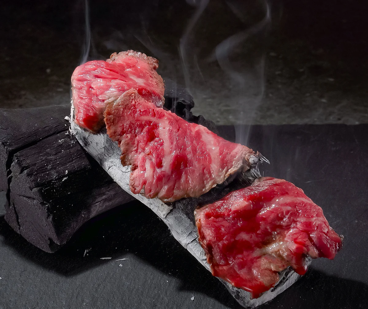 Slices of seared beef served on a hot stone with steam rising