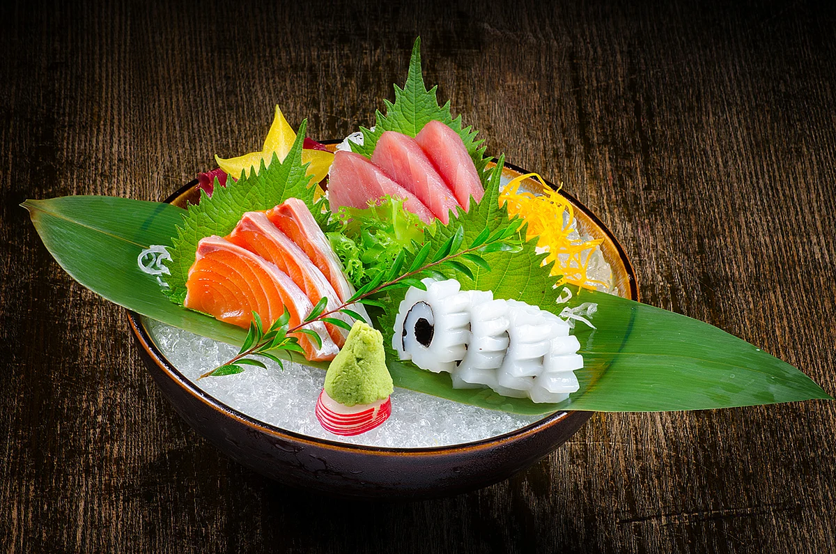 Assorted sashimi and seafood arranged on crushed ice with shiso leaves and wasabi